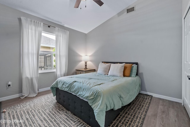 bedroom featuring lofted ceiling, wood finished floors, visible vents, and baseboards