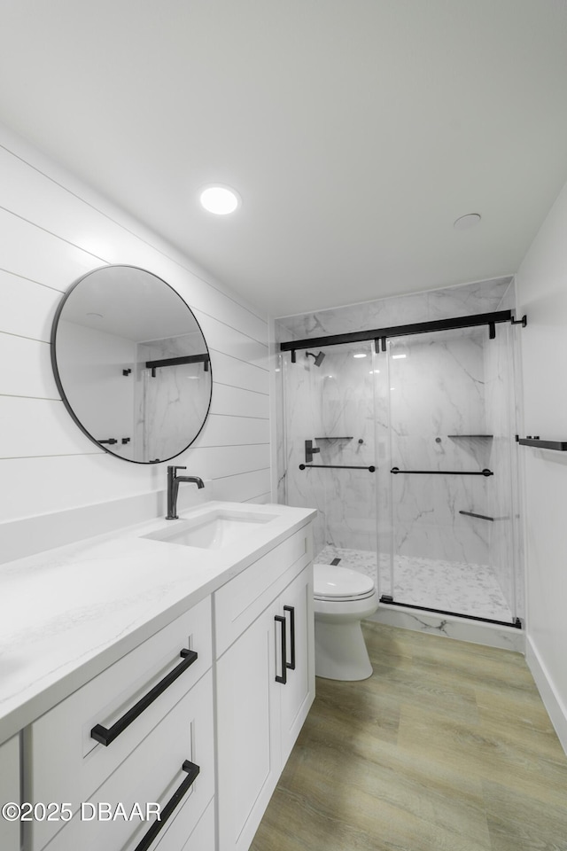 bathroom with hardwood / wood-style flooring, vanity, toilet, and an enclosed shower