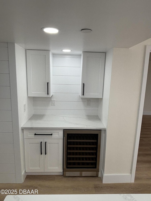 bar featuring white cabinetry, light stone countertops, wine cooler, and light wood-type flooring