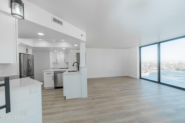 kitchen with appliances with stainless steel finishes, white cabinetry, sink, backsplash, and expansive windows