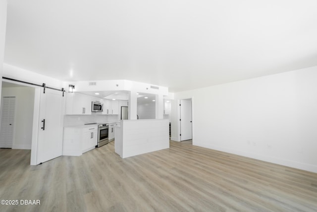 unfurnished living room featuring a barn door and light hardwood / wood-style floors