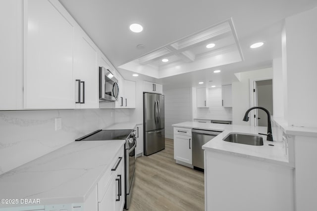 kitchen featuring coffered ceiling, sink, light stone counters, stainless steel appliances, and white cabinets