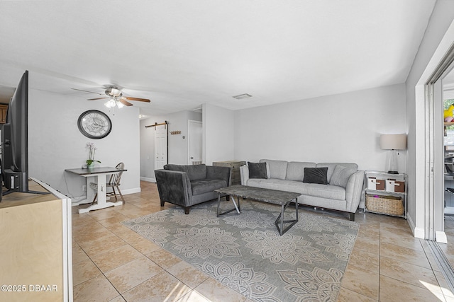 living room with light tile patterned floors, a barn door, visible vents, baseboards, and a ceiling fan