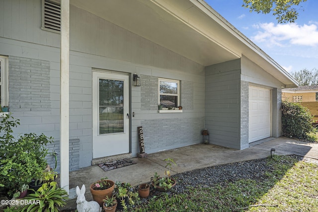 doorway to property featuring brick siding and an attached garage