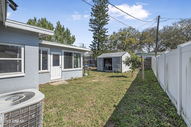 view of yard featuring a fenced backyard, a storage unit, central AC, and an outbuilding