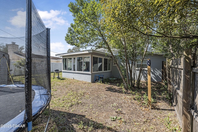 exterior space with a trampoline, fence, and a sunroom