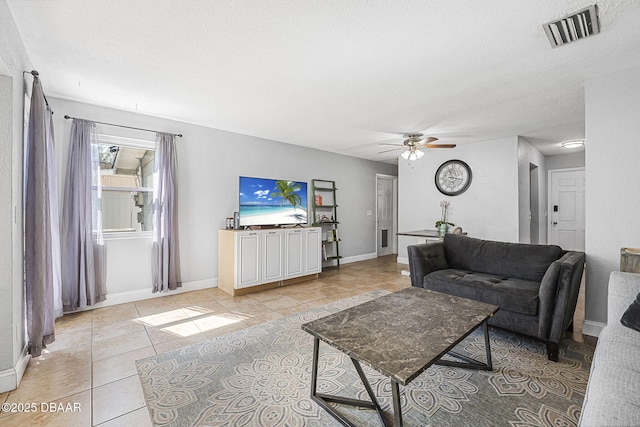 living area with light tile patterned floors, baseboards, visible vents, and a textured ceiling