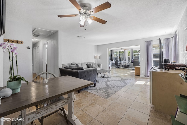 living room with light tile patterned floors, ceiling fan, visible vents, and a textured ceiling