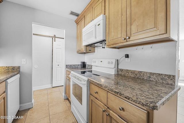 kitchen with white appliances, a barn door, light tile patterned floors, visible vents, and baseboards