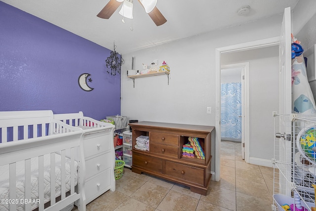 bedroom with a nursery area, ceiling fan, light tile patterned flooring, and baseboards