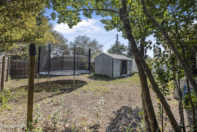 view of yard featuring a storage shed, a trampoline, an outdoor structure, and a fenced backyard