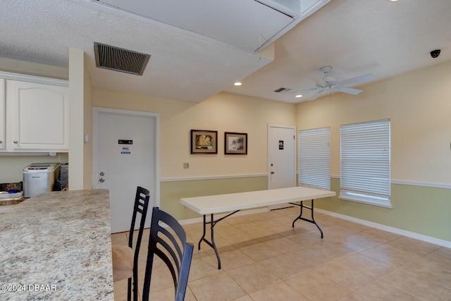 tiled dining space with a textured ceiling and ceiling fan