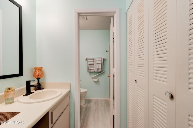 bathroom featuring hardwood / wood-style flooring, vanity, toilet, and a textured ceiling