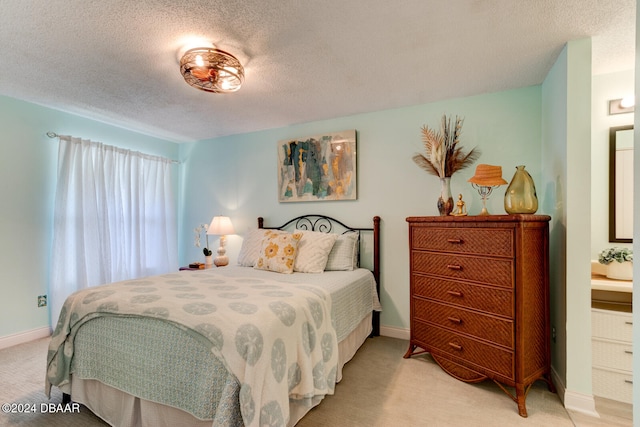 carpeted bedroom featuring a textured ceiling and ensuite bath