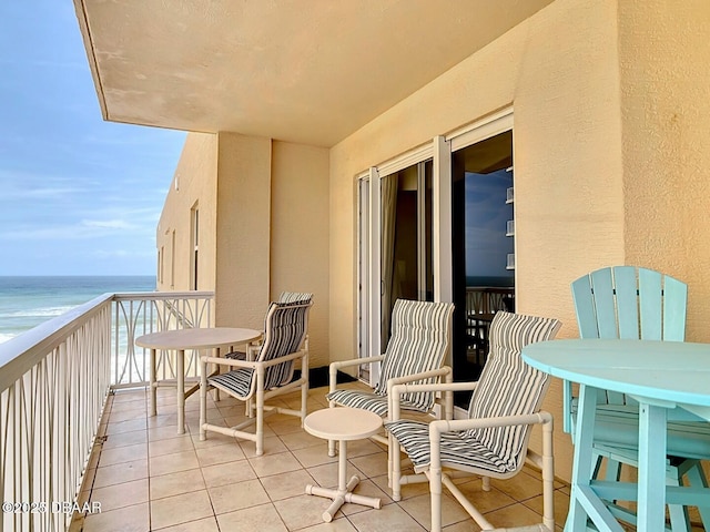 balcony with a water view and a view of the beach