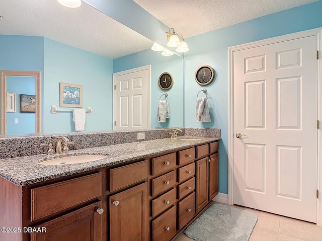 full bath with double vanity, tile patterned flooring, a textured ceiling, and a sink