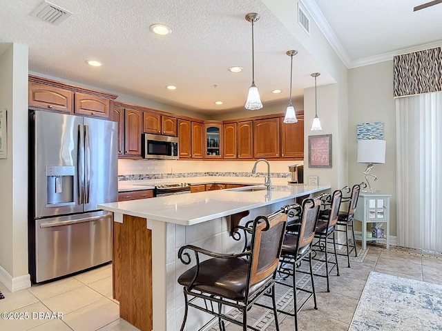 kitchen featuring appliances with stainless steel finishes, a breakfast bar area, glass insert cabinets, and visible vents