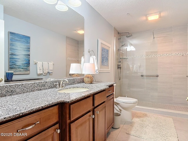 full bath featuring a textured ceiling, tiled shower, vanity, and toilet