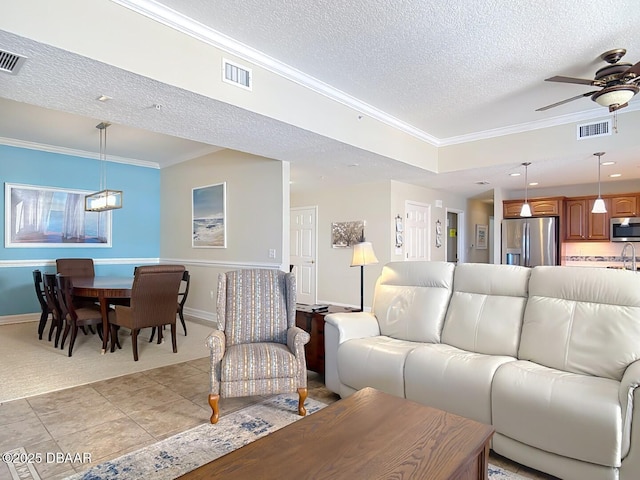 living room with light tile patterned flooring, visible vents, a textured ceiling, and ornamental molding