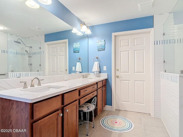 bathroom featuring double vanity, tile patterned flooring, a sink, and a shower stall