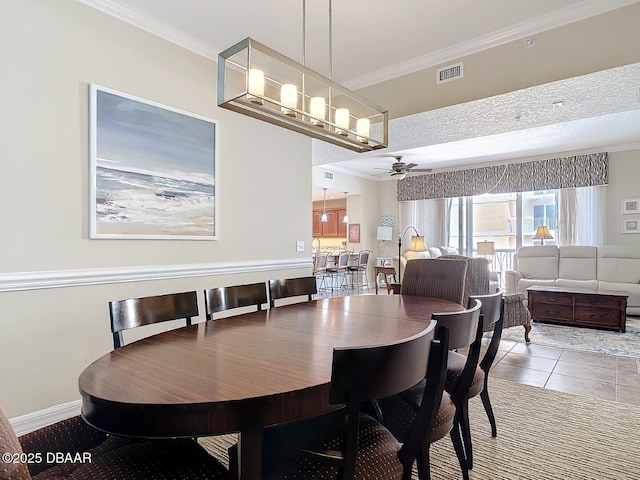 tiled dining room featuring ceiling fan, baseboards, visible vents, and crown molding