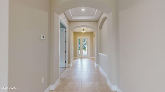 entryway with light tile patterned flooring and a raised ceiling