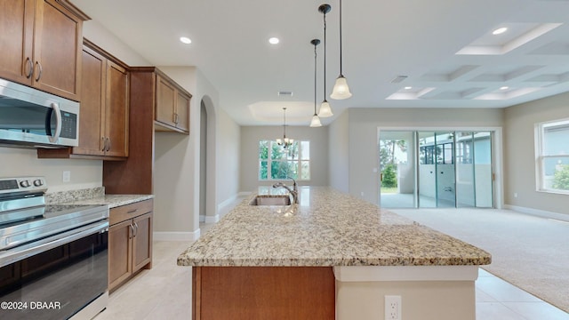 kitchen with a kitchen island with sink, appliances with stainless steel finishes, hanging light fixtures, and sink