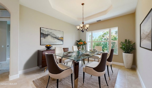 tiled dining room with a raised ceiling and an inviting chandelier