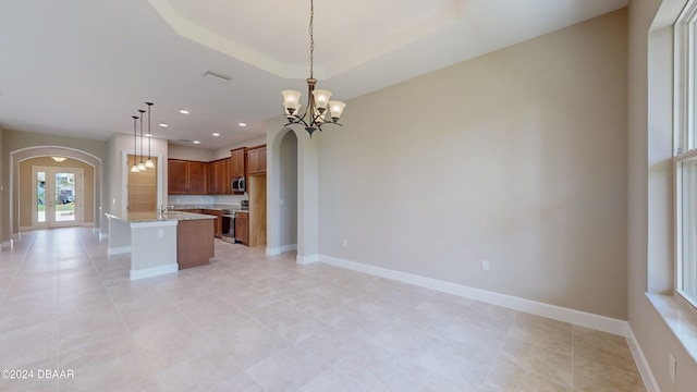 kitchen with decorative light fixtures, stainless steel appliances, light stone countertops, an inviting chandelier, and french doors