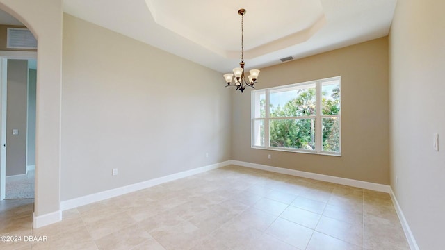 spare room featuring light tile patterned flooring, a notable chandelier, and a tray ceiling