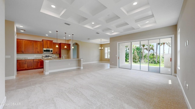 unfurnished living room with beamed ceiling, coffered ceiling, light colored carpet, and an inviting chandelier