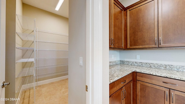 pantry featuring light stone counters and light tile patterned floors