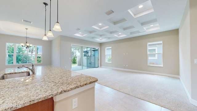 kitchen featuring an inviting chandelier, light carpet, sink, light stone countertops, and pendant lighting