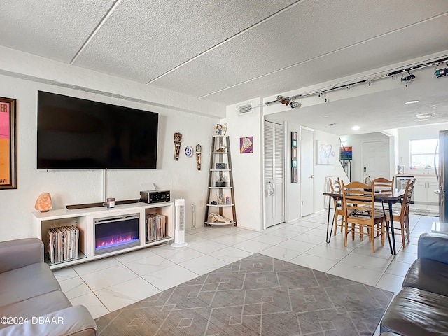 tiled living room featuring track lighting and a textured ceiling