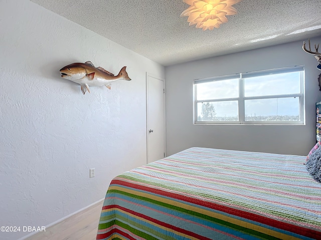 bedroom with a textured ceiling and hardwood / wood-style flooring