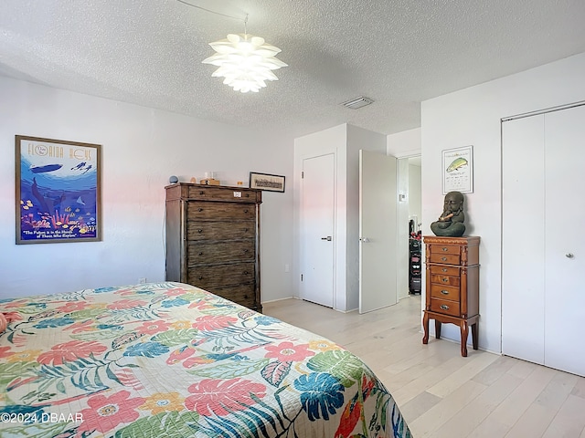 bedroom featuring light hardwood / wood-style floors and a textured ceiling