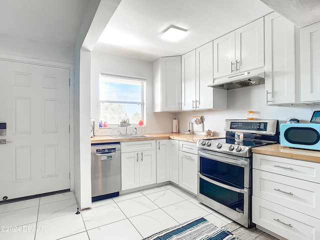1510 Ocean Shore Blvd Unit 406, Ormond Beach, FL 32176 - kitchen featuring appliances with stainless steel finishes, under cabinet range hood, butcher block counters, a sink, and white cabinetry