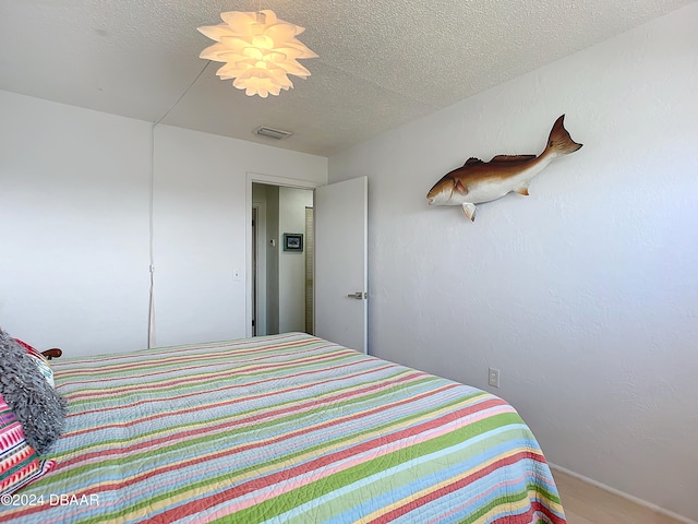 bedroom with hardwood / wood-style floors and a textured ceiling