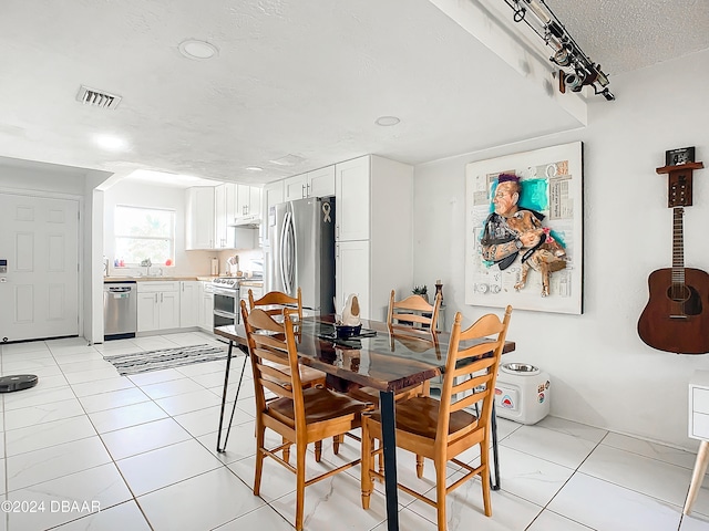 tiled dining space featuring a textured ceiling and sink