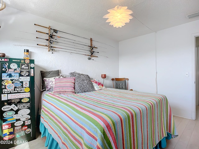 bedroom with a textured ceiling and light hardwood / wood-style floors