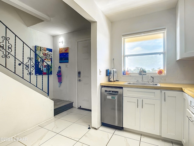 kitchen featuring stainless steel dishwasher, wood counters, white cabinets, and sink