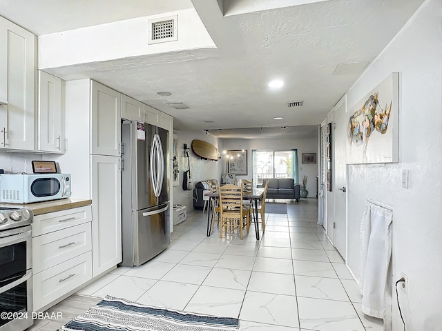 kitchen featuring white cabinets, stainless steel appliances, and a textured ceiling