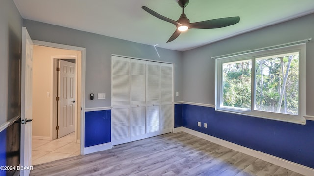 unfurnished bedroom featuring ceiling fan, light wood-type flooring, and a closet