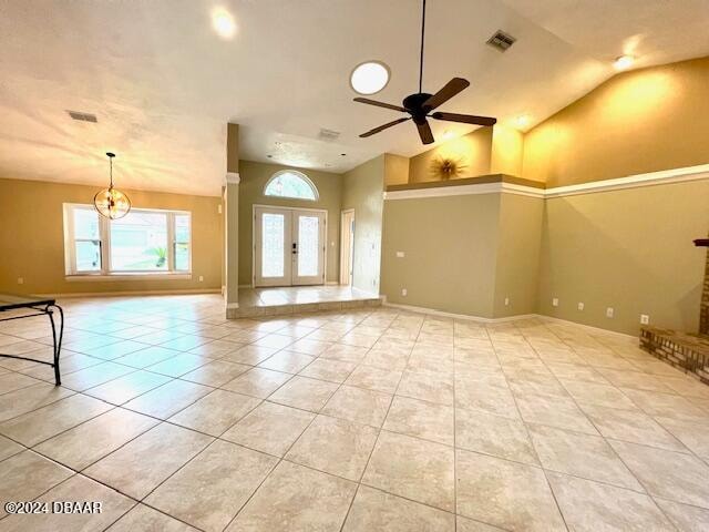 tiled spare room featuring french doors, ceiling fan with notable chandelier, and lofted ceiling