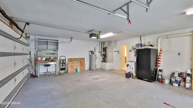 garage featuring heating unit, electric water heater, black refrigerator, and a garage door opener