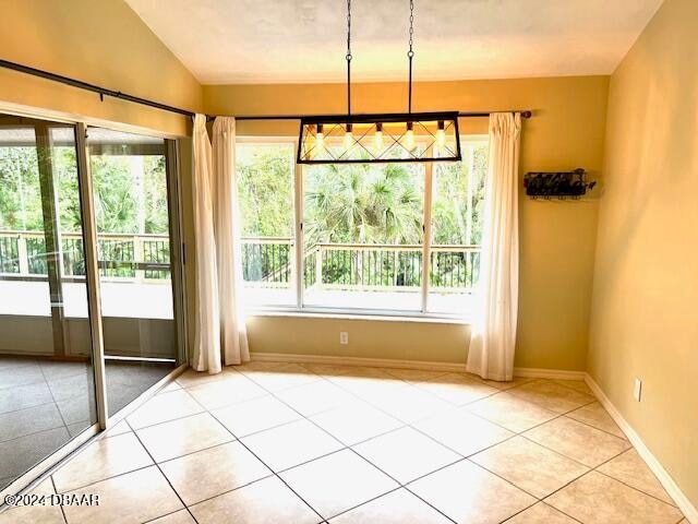 interior space with plenty of natural light, light tile patterned floors, and vaulted ceiling