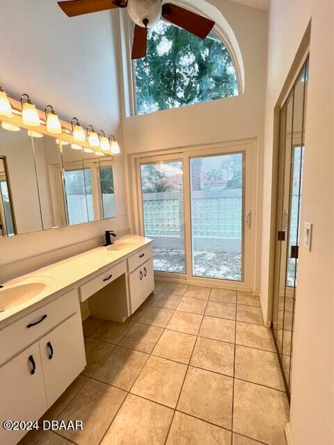 bathroom with tile patterned floors, vanity, ceiling fan, and a high ceiling