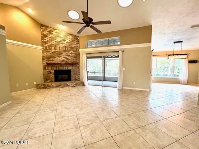 unfurnished living room featuring a fireplace, ceiling fan, a healthy amount of sunlight, and light tile patterned flooring