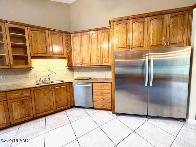 kitchen featuring light stone countertops, sink, light tile patterned floors, and appliances with stainless steel finishes