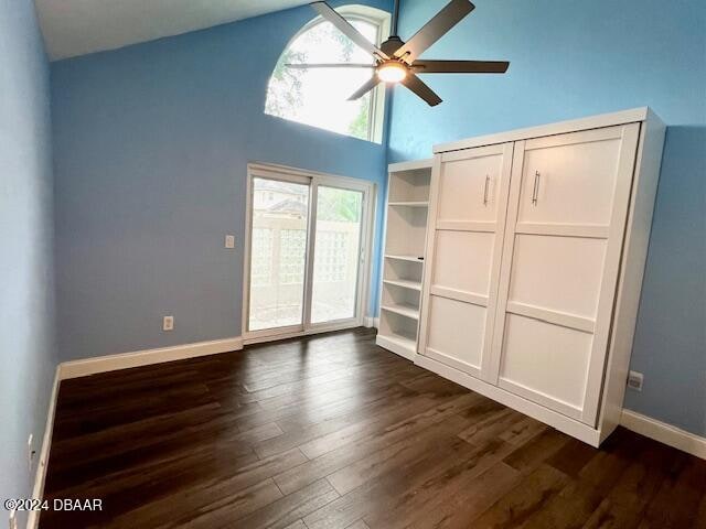 unfurnished bedroom with access to outside, ceiling fan, high vaulted ceiling, and dark hardwood / wood-style floors